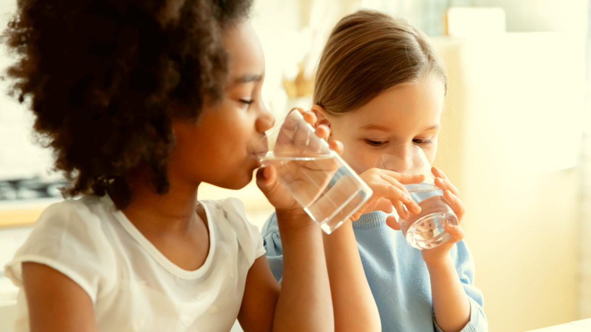 Two children drinking water from glasses, highlighting the importance of hydration for cognitive performance in children. Cleartide provides bottleless water solutions in Boston.