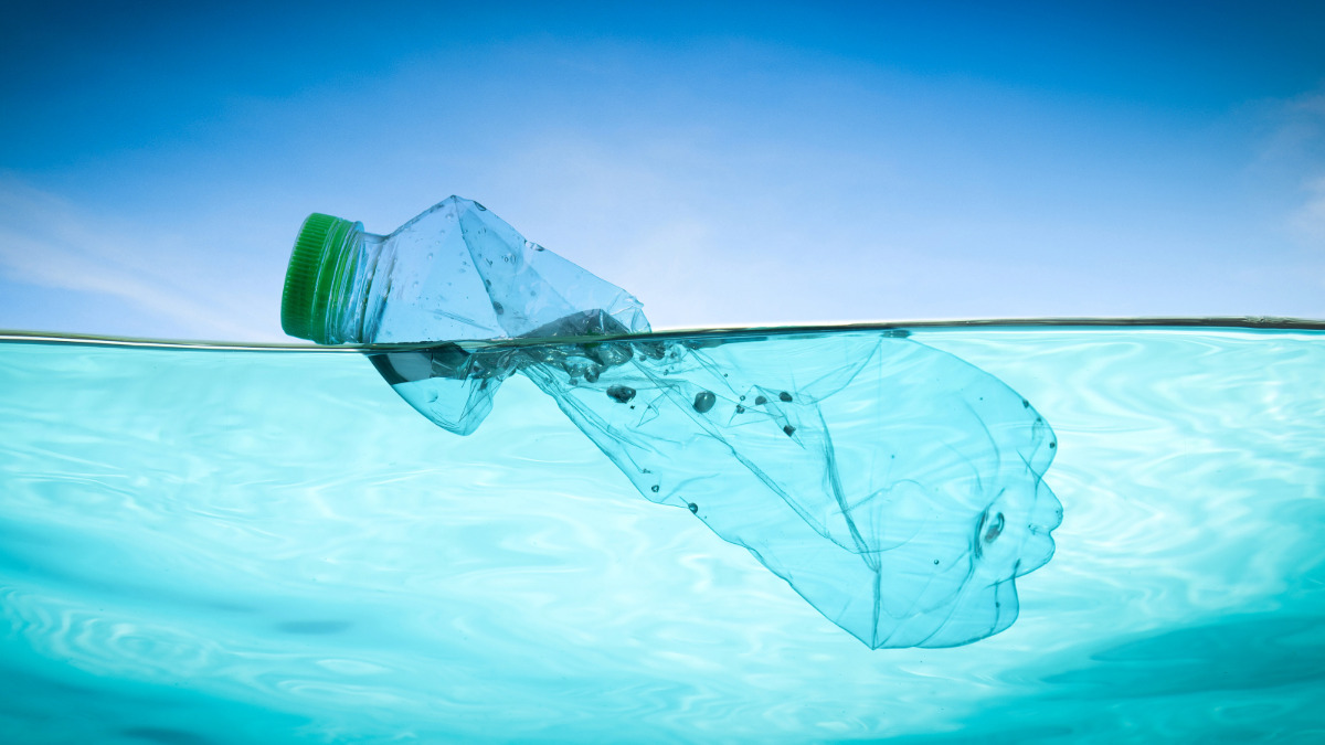 Plastic bottle floating in water, illustrating the environmental impact of plastic pollution and Cleartides bottle-free hydration solutions for sustainability.